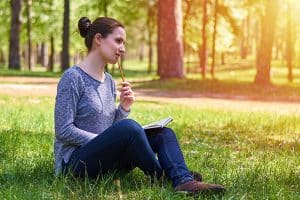 Beautiful young lady in nature taking notes on a notepad